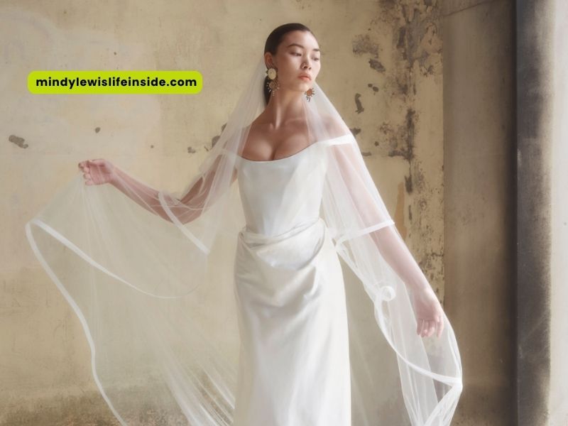 A woman wearing a Vivienne Westwood wedding dress poses with her veil, highlighting the intricate design and beauty.