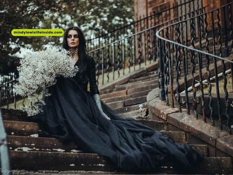 A woman in a black dress sits on stairs, contemplating the appropriateness of wearing black to a wedding.