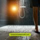 A person stands in a shower with water running, contemplating whether to wear flip flops in the gym shower.