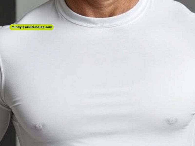 A man in a white shirt and black belt, contemplating whether to wear an undershirt.
