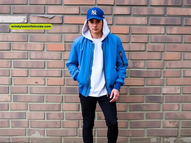 A young man in a blue bomber jacket over a white shirt, showcasing a stylish casual outfit.