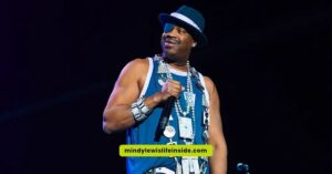 On stage, a man in a blue shirt and hat captivates the audience, reminiscent of Slick Rick's iconic eyepatch look.