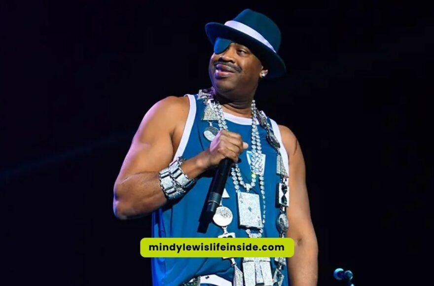 On stage, a man in a blue shirt and hat captivates the audience, reminiscent of Slick Rick's iconic eyepatch look.