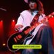 A guitarist performing on stage with another man, both contributing to an engaging live music experience.