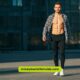 A shirtless man stands in front of a building, embodying a casual attitude towards fashion and self-expression.