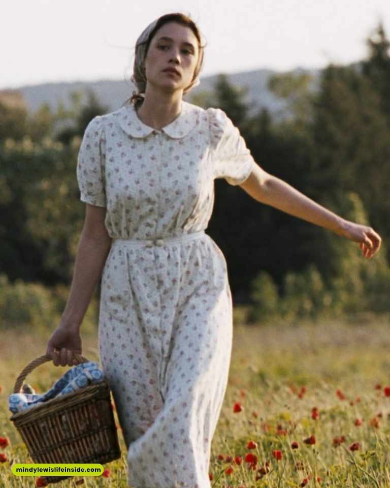 A woman in a stylish dress and hat strolls through a vibrant field of red poppies, embodying elegance in nature.