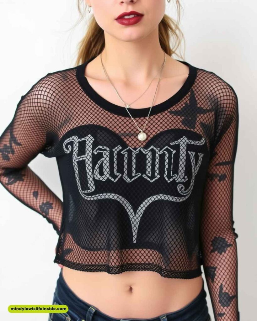 A woman wearing a black mesh crop top with "Haunty" in gothic font. She has red lipstick and a necklace, conveying a bold, edgy style.