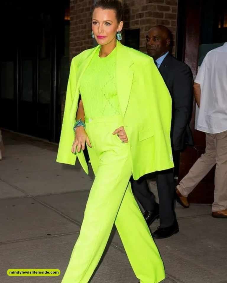 A woman in a vibrant neon green suit and heels, elegantly dressed for a celebrity event, exuding confidence and style.