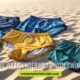 A variety of colorful swim trunks and briefs lie on a sandy beach. Text reads, "Should you wear underwear with swim trunks?" The mood is casual and summery.