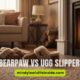 Cozy living room with slippers by a fireplace on a plush rug. Text reads "BEARPAW VS UGG SLIPPERS" against a warm, inviting atmosphere.